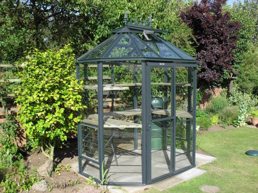 <strong>Renaissance OCTAGONAL:</strong> An attractive octagonal greenhouse that is 5’7 (1714mm) deep and available in four lengths: 5’7 (1714mm), 7’7 (2312mm), 9’7 (2932mm) and 11’8 (3552mm). Large pane 4mm toughened safety glass and bar capping included. Extremely strong box section framework. Staging & shelving as standard. Coloured finish.